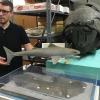 Lee Hall holds a model of a Cladoselache shark above the 360 million year old fossil impression that it's based on. A Dunkleosteous specimen looks on, part of CMNH's world famous collection of Devonian fish fossils.